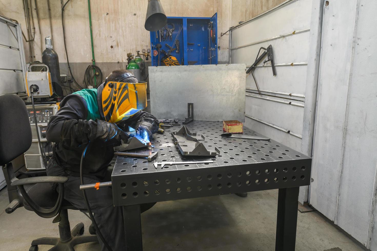 Professioneller Schweißer führt Arbeiten mit Metallteilen in der Fabrik, Funken und Strom durch. Banner für Industriearbeiter. foto