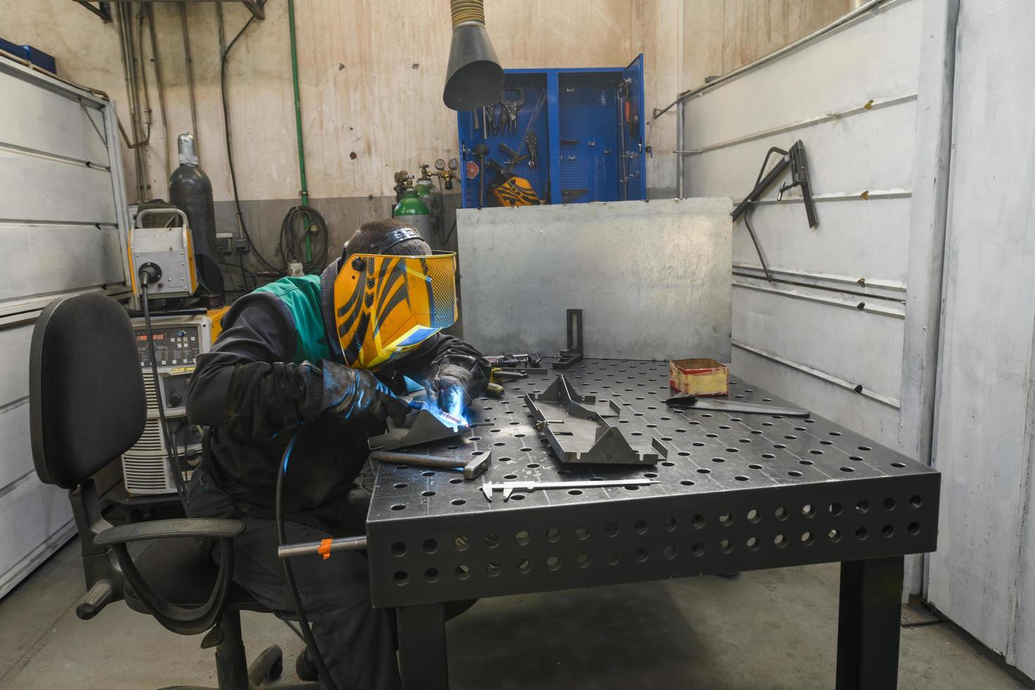 Professioneller Schweißer führt Arbeiten mit Metallteilen in der Fabrik, Funken und Strom durch. Banner für Industriearbeiter. foto