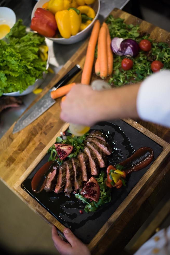 Blick von oben auf den Koch, der Steak-Fleischplatte fertigstellt foto