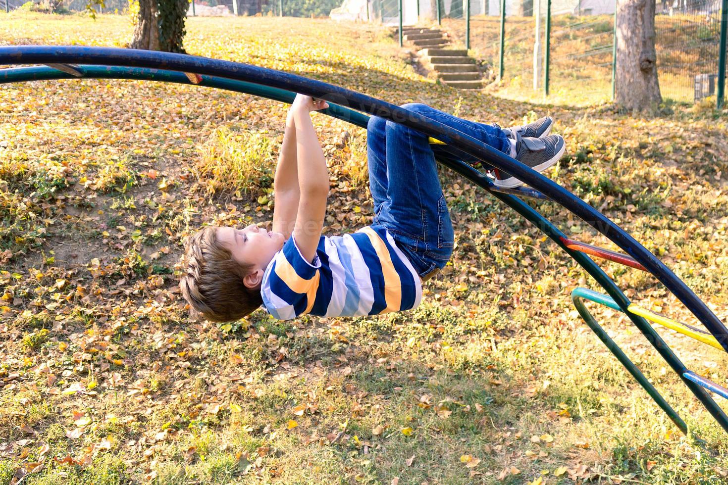 sorgloser junge, der auf dem spielplatz in der natur spielt. foto