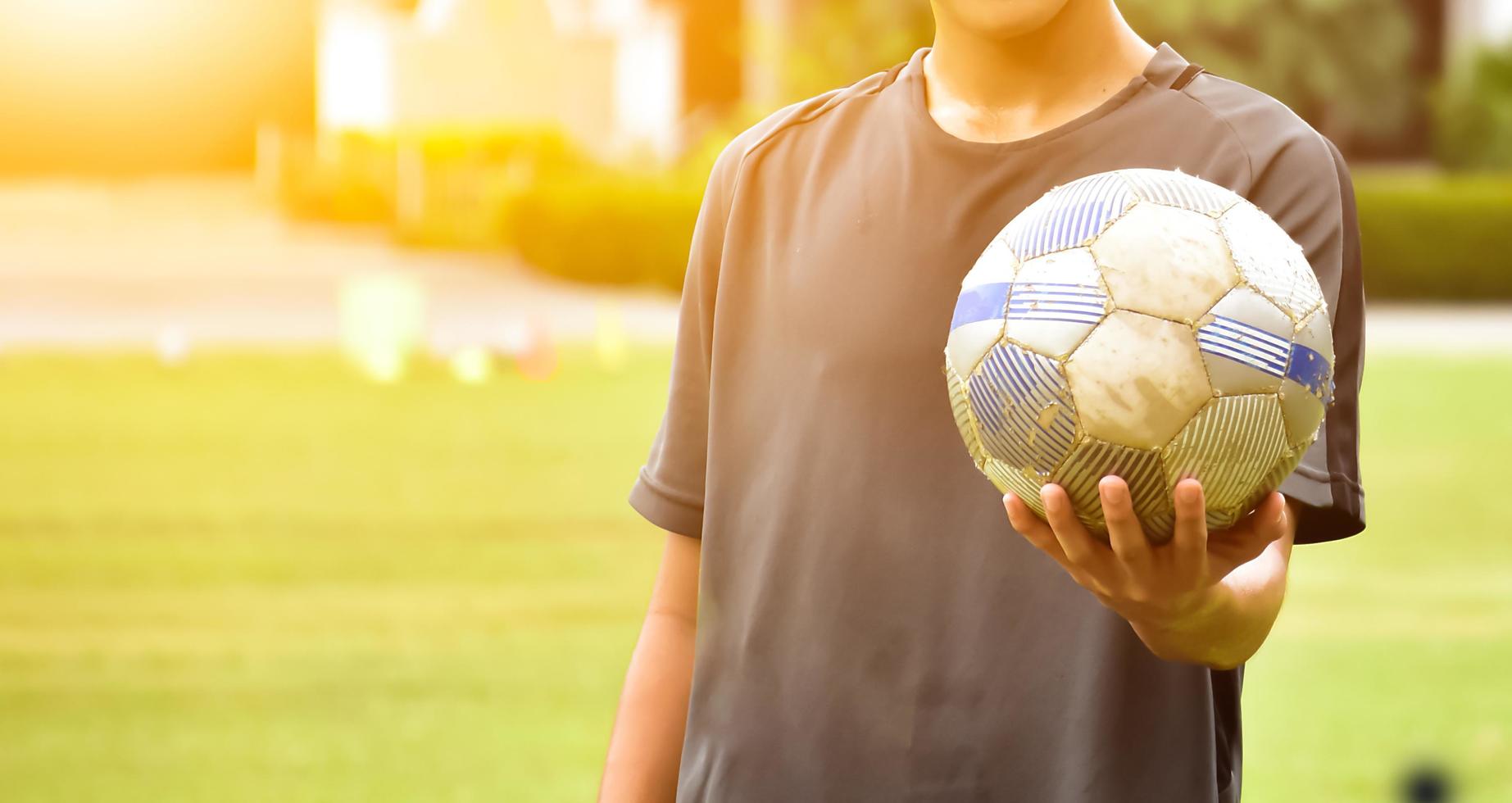 ein alter fußball, der in der hand des spielers hält, weicher und selektiver fokus auf fußball, sonnenlicht bearbeiteter hintergrund. foto