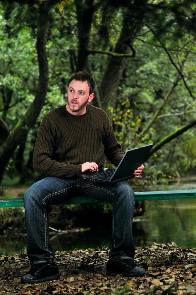 Junger Geschäftsmann, der am Laptop im Freien arbeitet foto