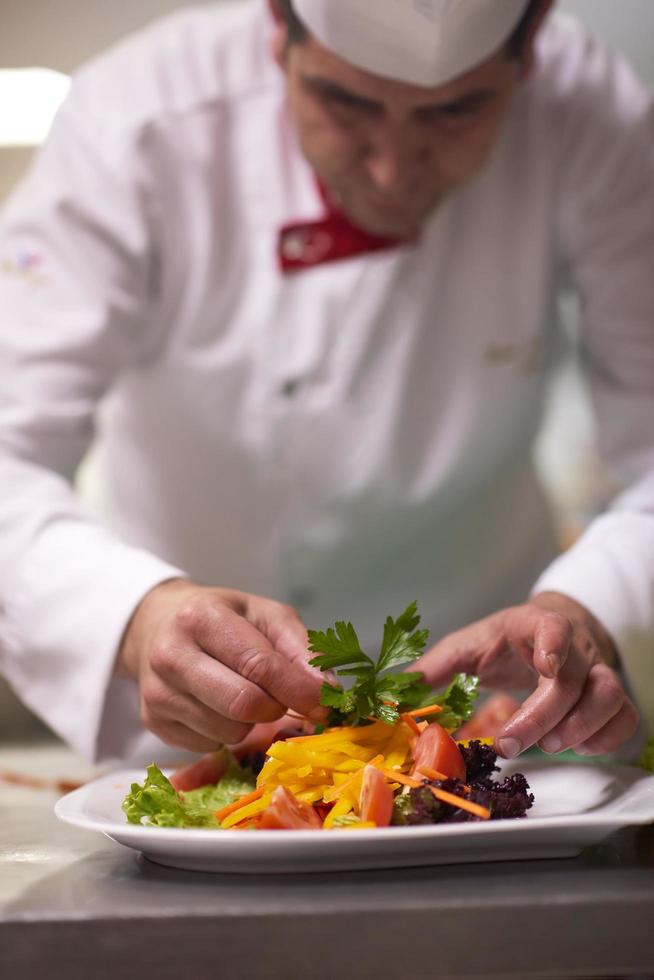 Küchenchef in der Hotelküche bereitet Speisen zu und dekoriert sie foto