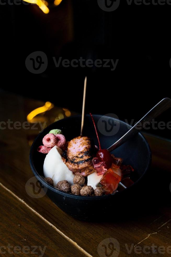 Eisdessert mit süßen Toppings, verbranntem Marshmallow, farbigem Müsli, Schokoladen-Müsli, Gummibärchen in Panda-Form, Reis foto