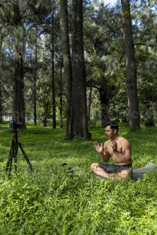 Blick auf einen Mann, der einen virtuellen Fitnesskurs mit einer Gruppe von Menschen zu Hause bei einer Videokonferenz durchführt. Fitnesstrainer, der Online-Yoga-Kurse nimmt foto