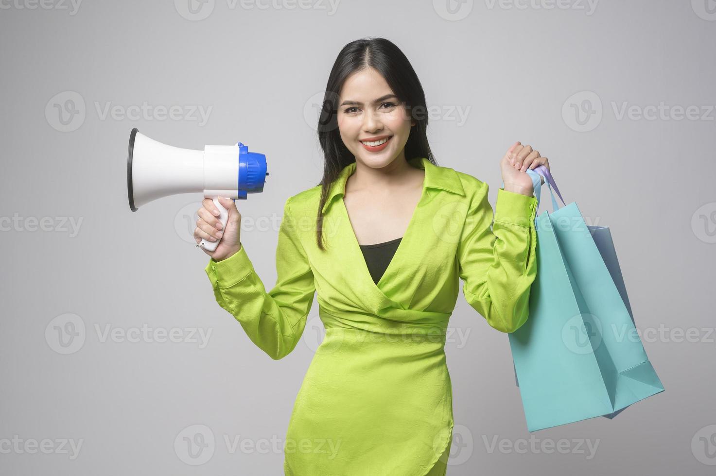 schöne Frau mit Megaphon und Einkaufstasche auf weißem Hintergrund Studio-, Einkaufs- und Finanzkonzept. foto