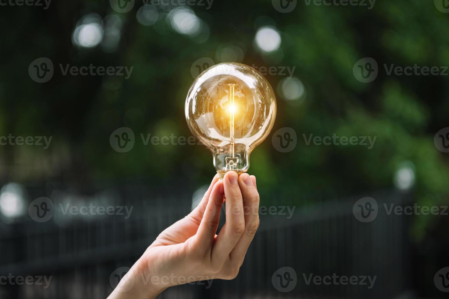 Hand, die Glühbirne mit grünem Hintergrund hält. Idee Solarenergie im Naturkonzept foto