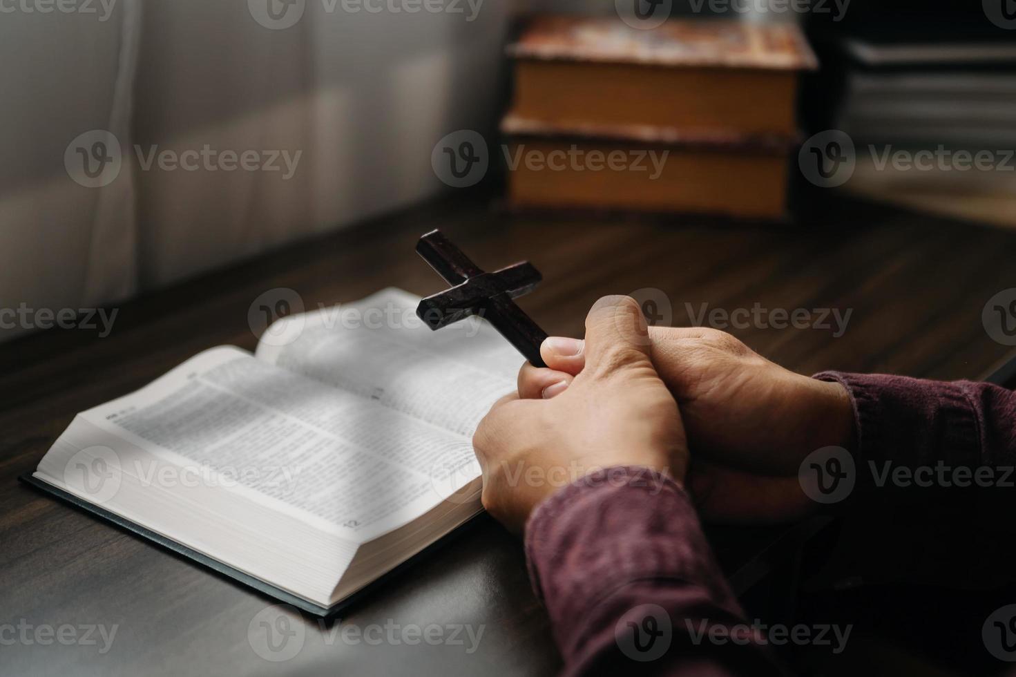 frau, die sitzt und die schriften studiert. das holzkreuz in den händen. christliche bildungskonzepte die heilige schrift öffnen und zu gott beten. foto