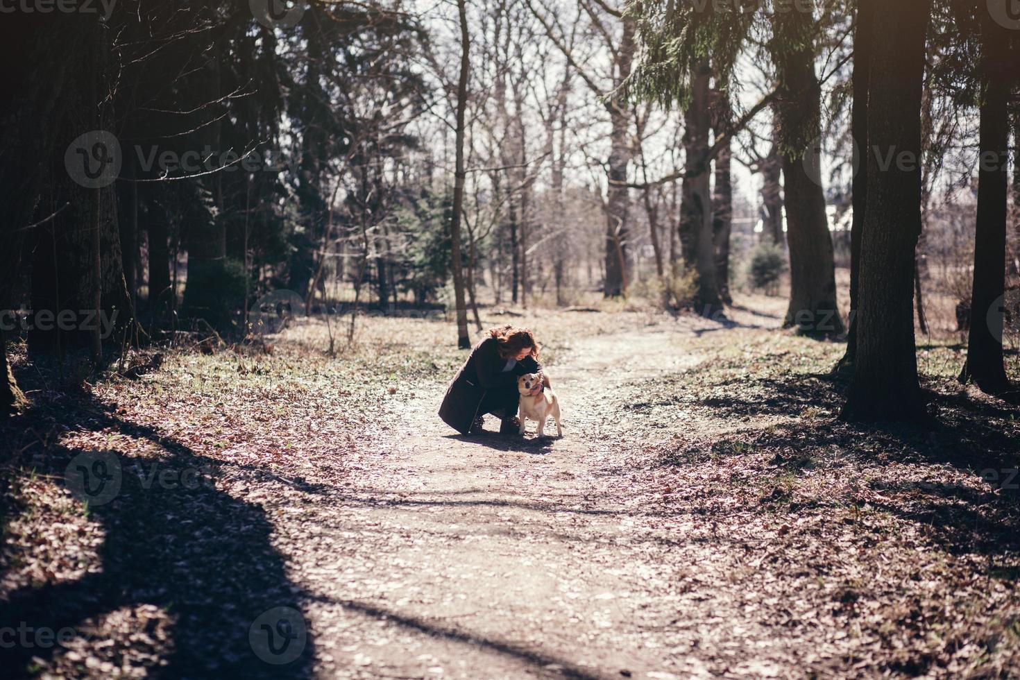 Mädchen in einem Mantel, der einen Hund umarmt foto