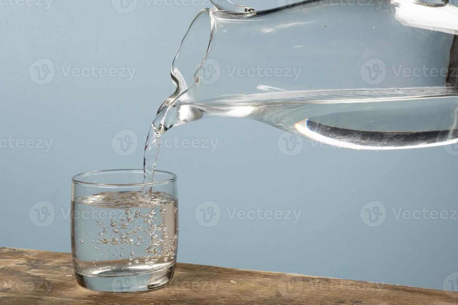 Person, die eine Tasse Wasser mit einem Glas füllt. foto