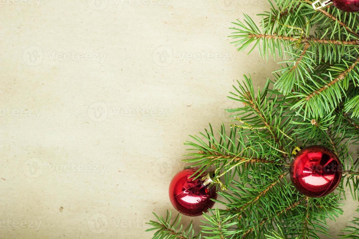 tannenzweige, die mit roten weihnachtskugeln als grenze auf einem rustikalen feiertagshintergrundrahmen mit kopienraum verziert sind foto