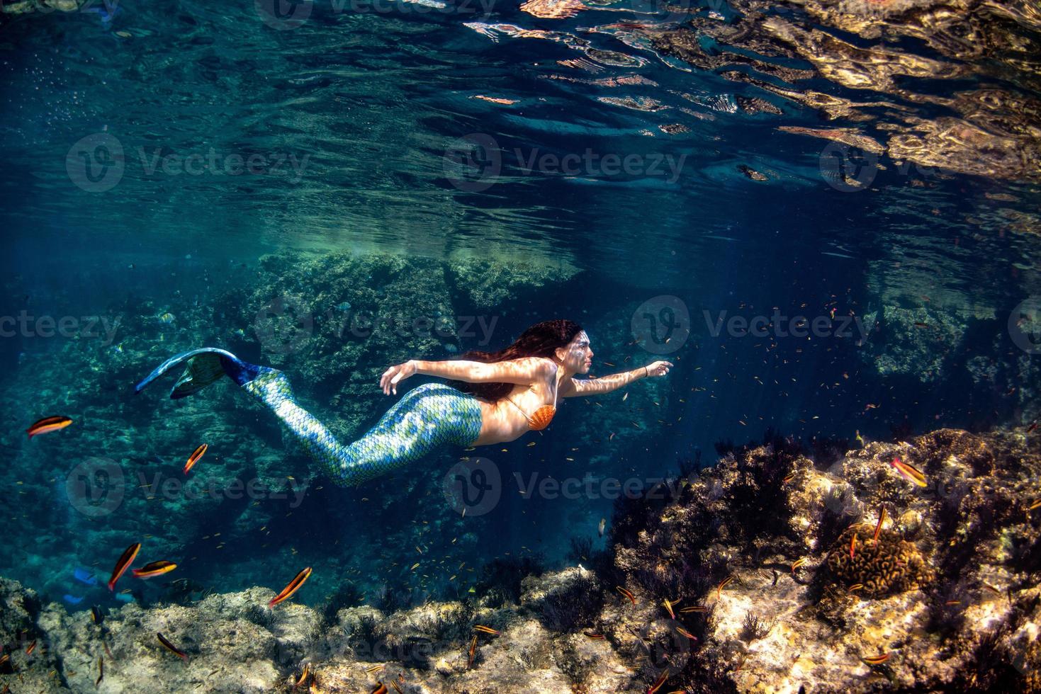 Meerjungfrau, die unter Wasser im tiefblauen Meer schwimmt foto