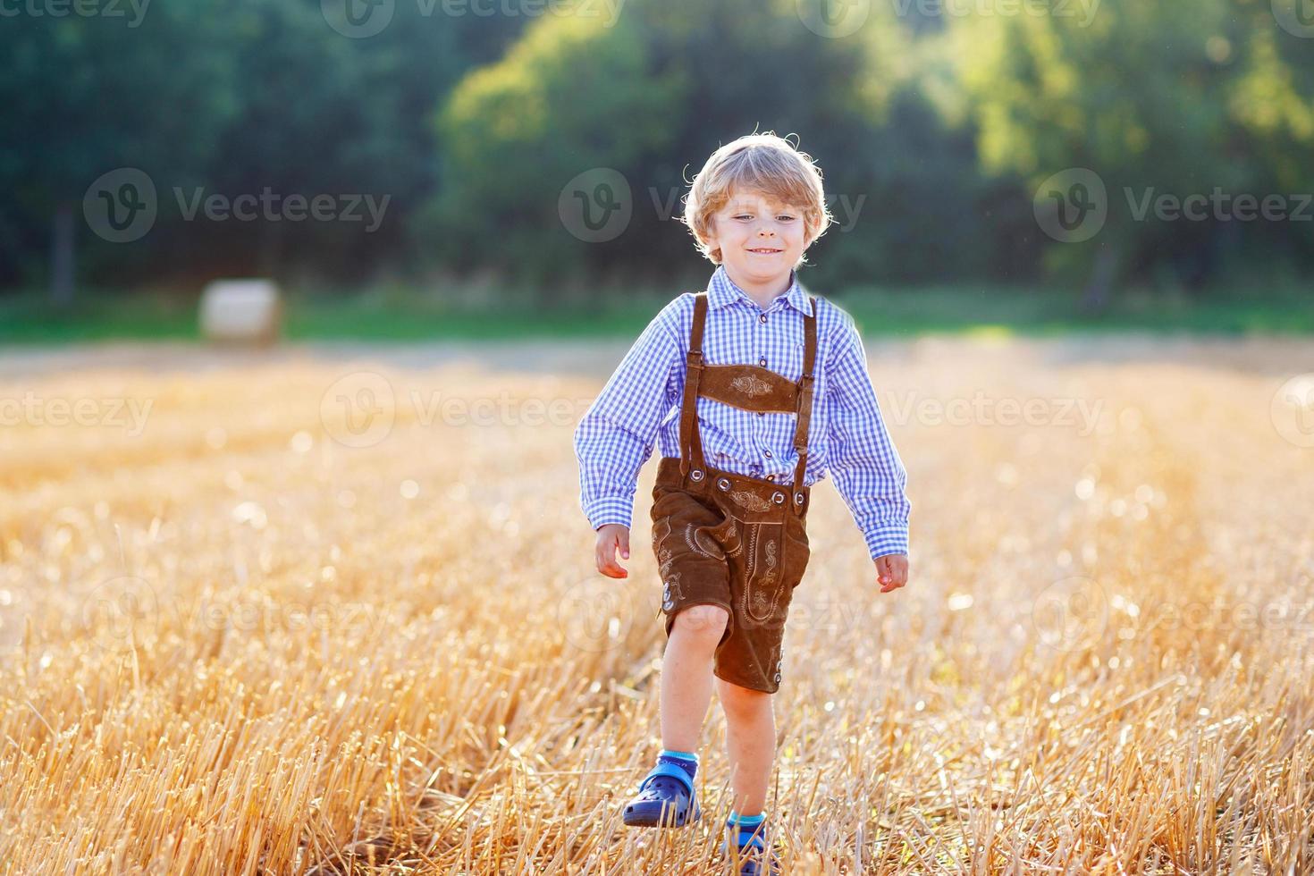 lustiger kleiner Junge in Ledershorts, die Weizenfeld gehen foto