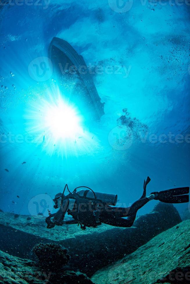 Bootsschiff aus blauem Unterwasserozean mit Sonnenstrahlen und Taucher foto