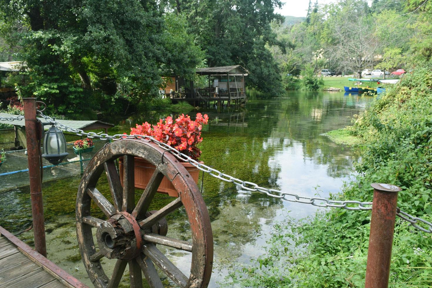 ein Teich, eine Brücke, ein Rad mit Blumen. Landschaftsdesign foto