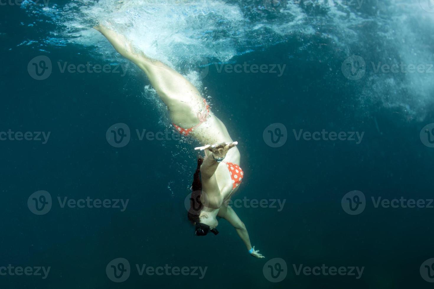 schönes Mädchen, das unter einem Schiff schwimmt foto