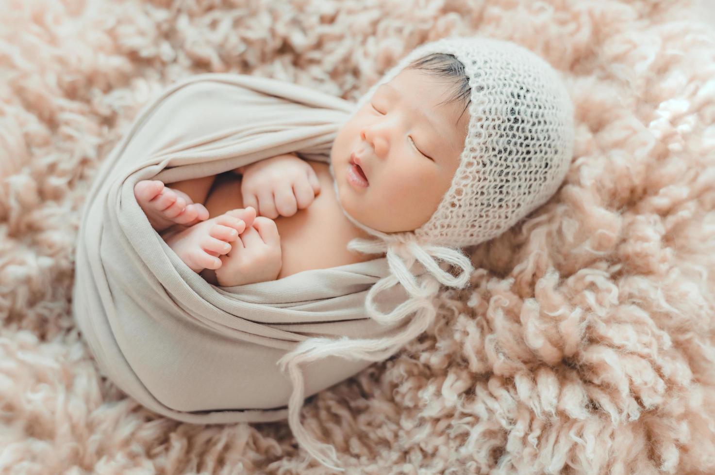 Neugeborene Babywickel im Kokon, der auf Pelz schläft foto