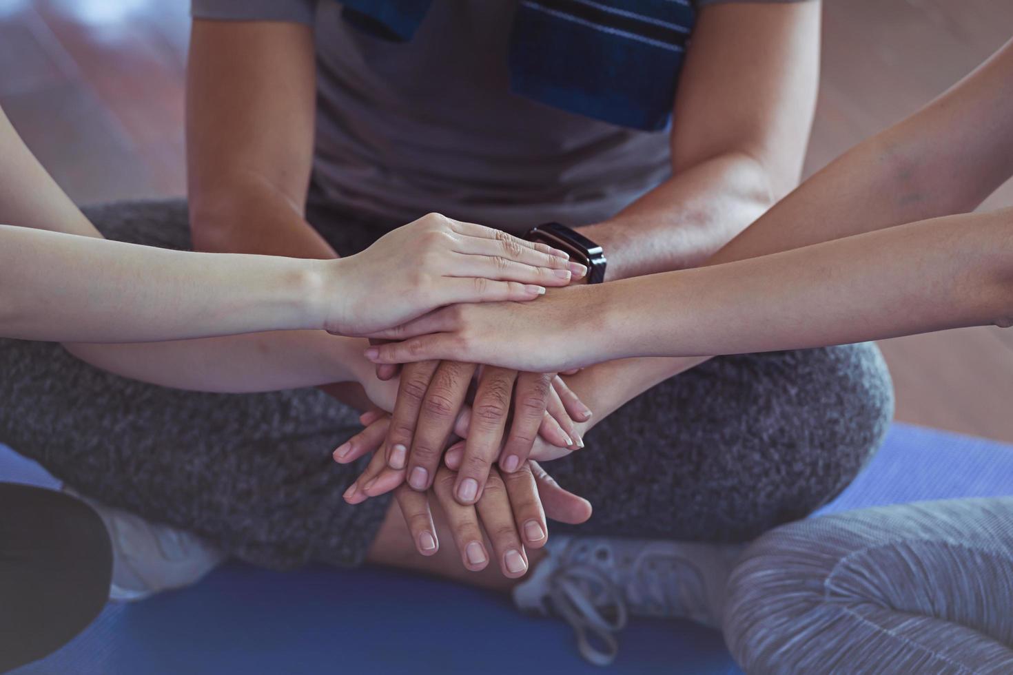 drei Erwachsene mit den Händen zusammen im Fitnessstudio. foto