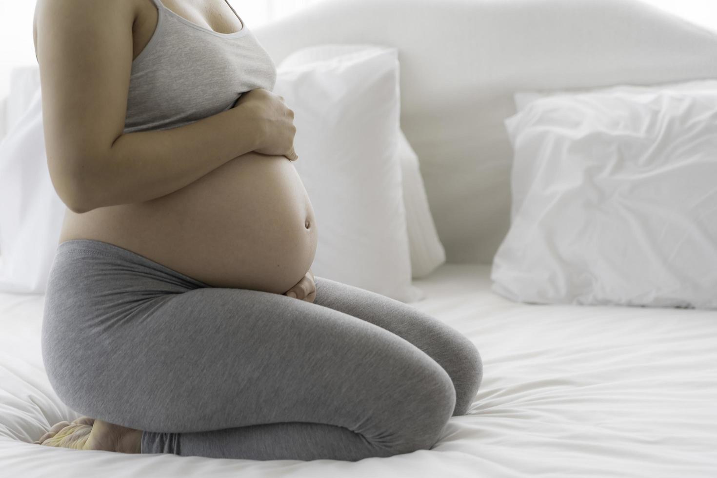 schöne asiatische schwangere Frau auf dem Bett foto
