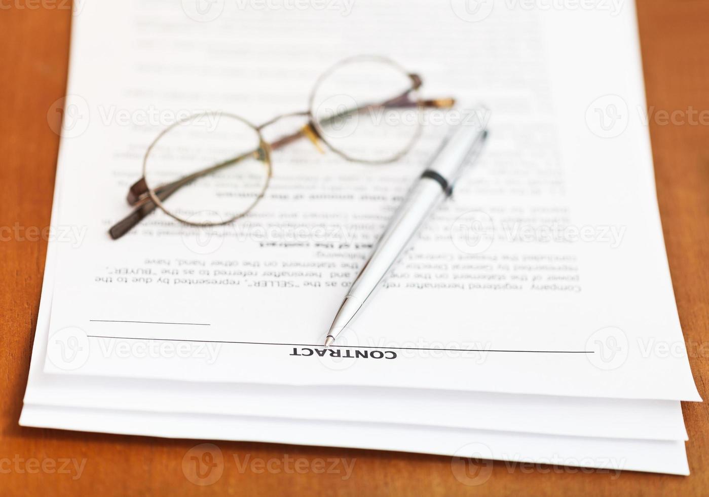 Vertrag und silberner Stift und Brille auf dem Tisch foto