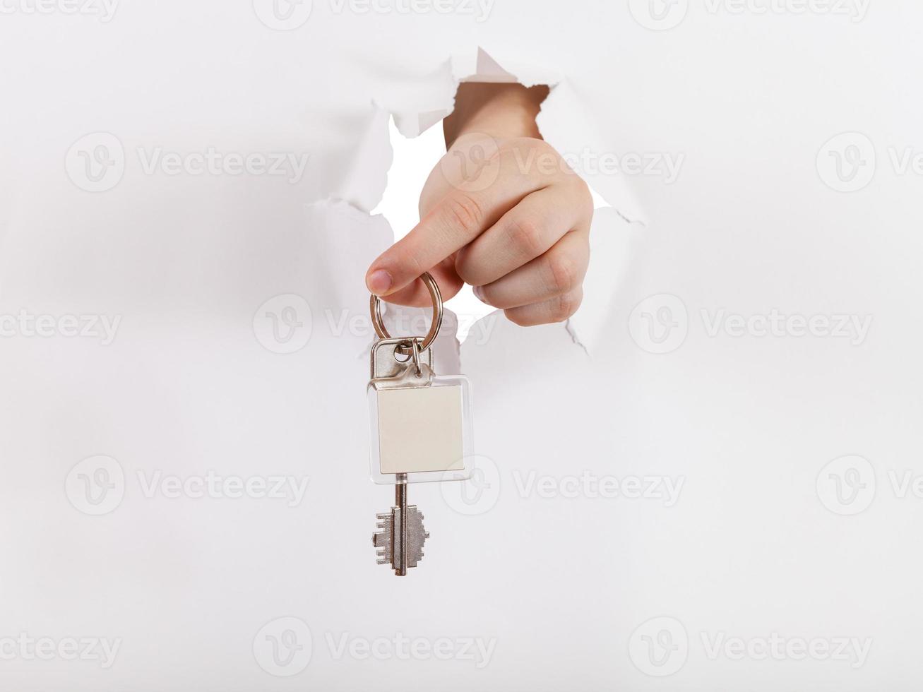 Hand hält den Schlüssel durch ein Loch foto