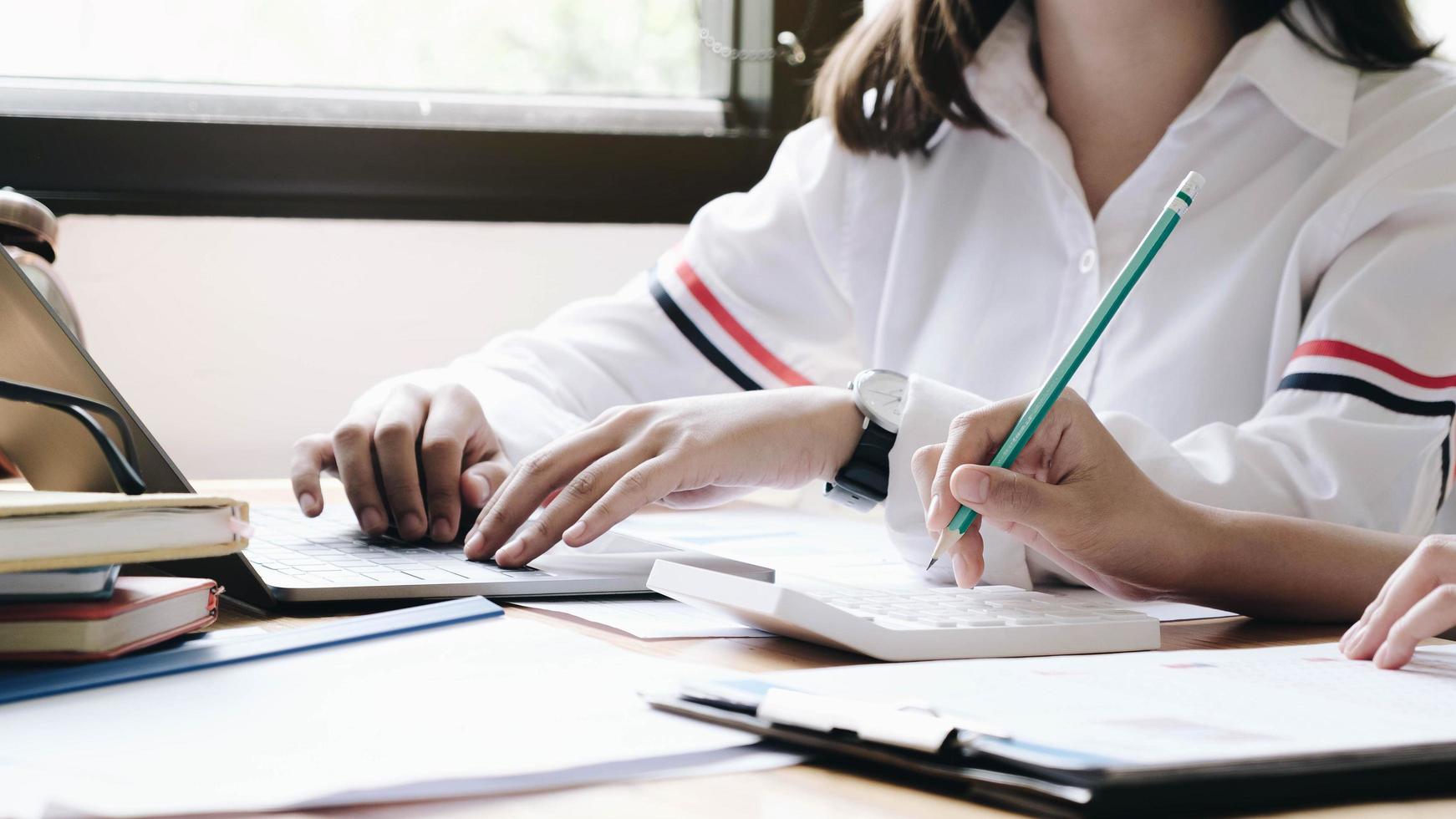 Mitarbeiter arbeiten gemeinsam an Laptop und Taschenrechner foto