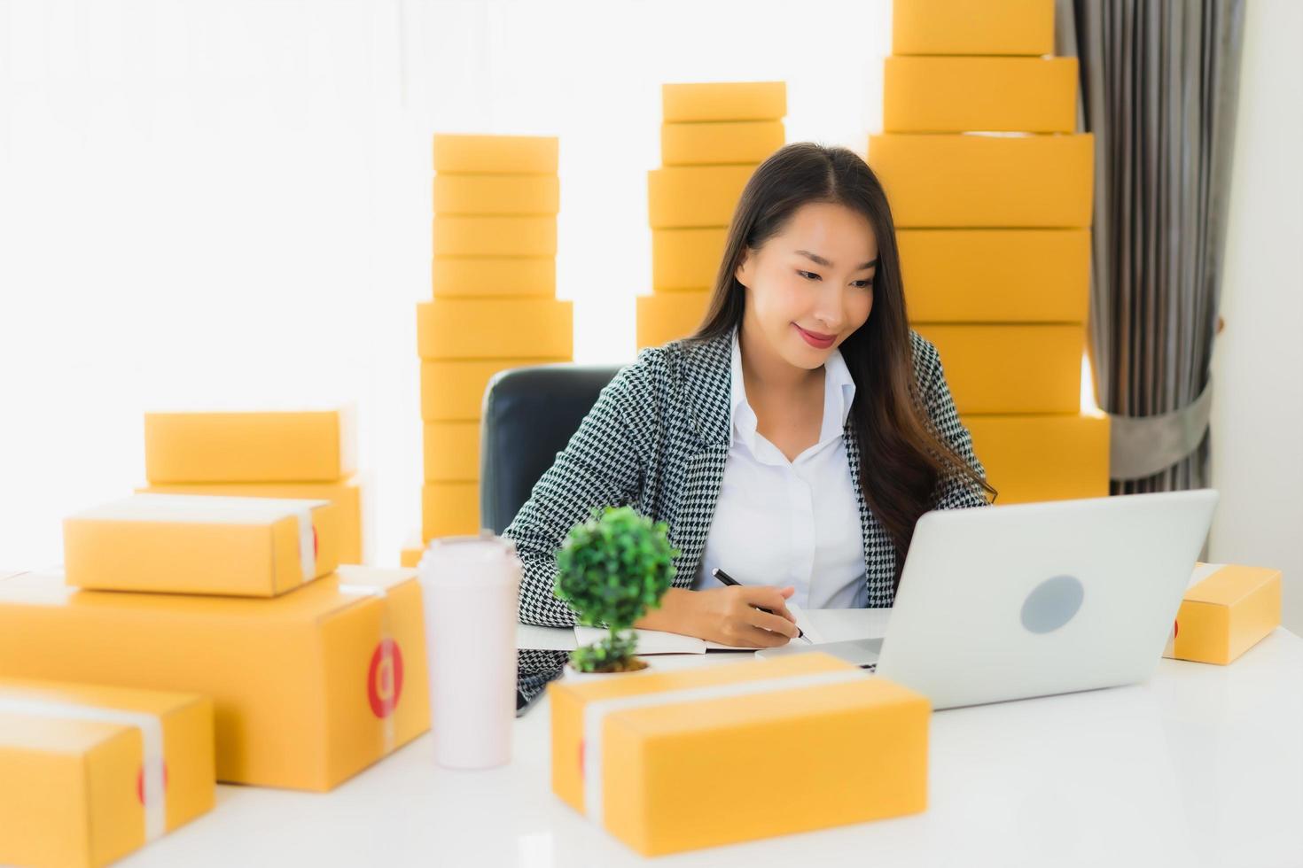 Frau arbeitet am Laptop mit Paketen um sie herum foto