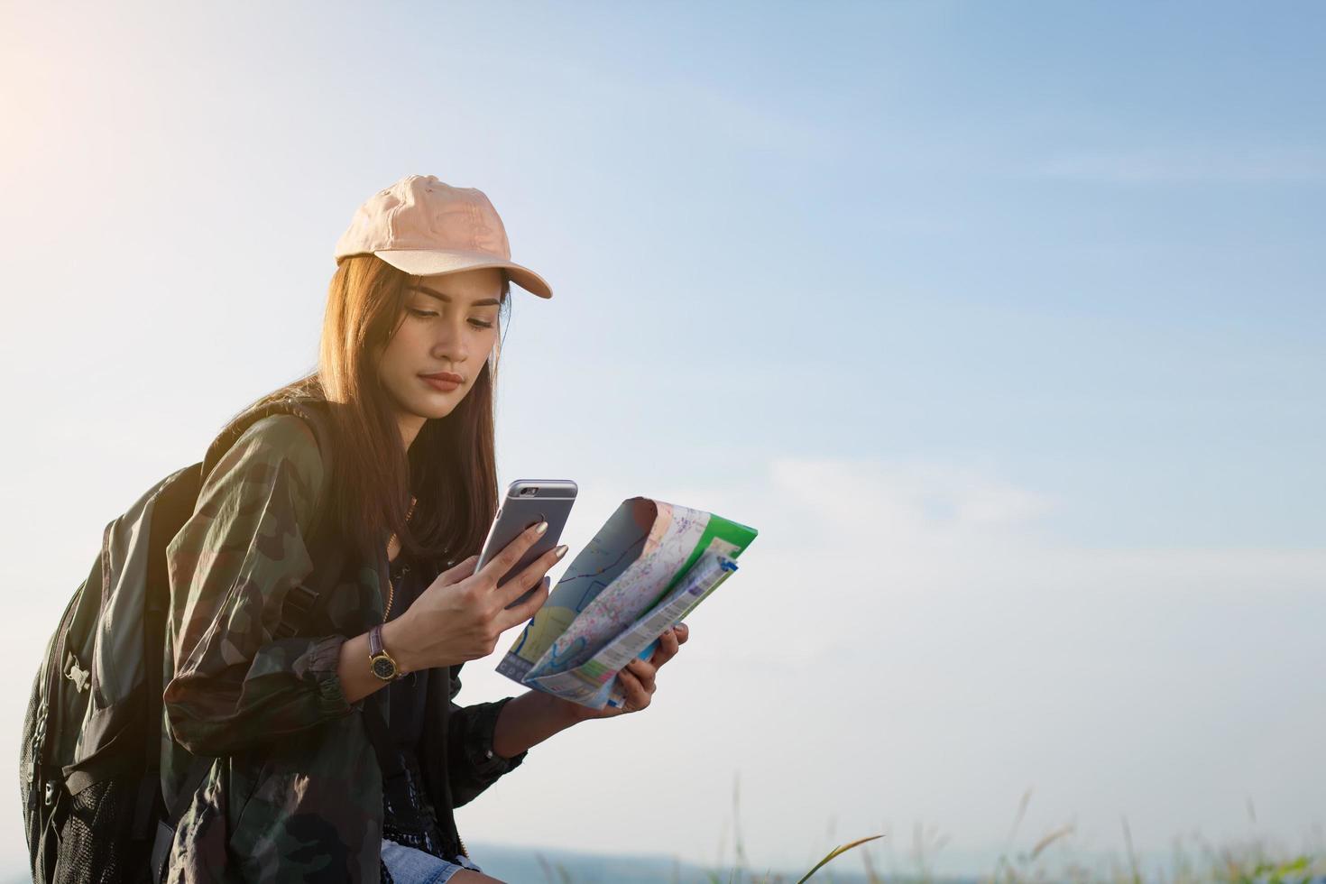 Frau, die mit Karte und Telefon in Händen navigiert foto