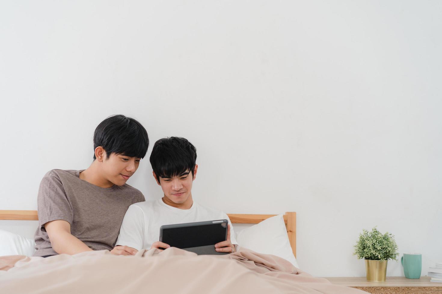 junges asiatisches schwules Paar, das Tablette zu Hause benutzt foto