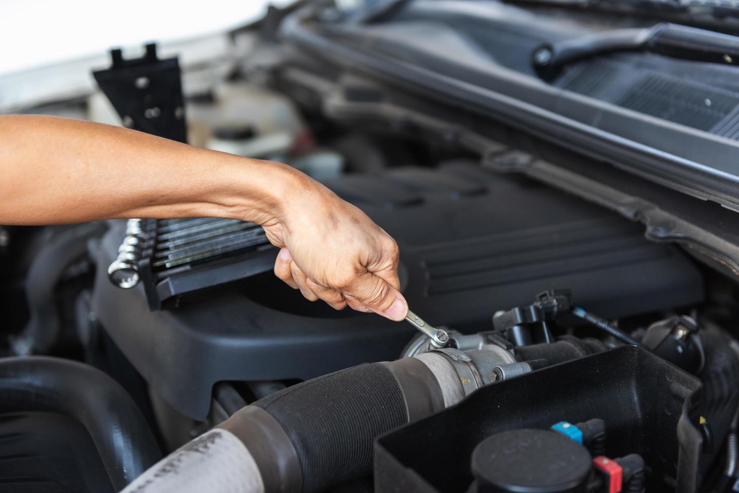 Mann mit Schraubenschlüssel am Automotor foto