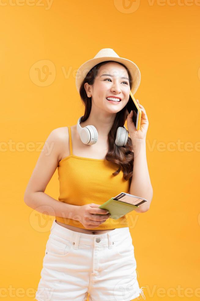 lange haare der asiatischen frau tragen strohhut in der hand, die passbuch und handy hält foto