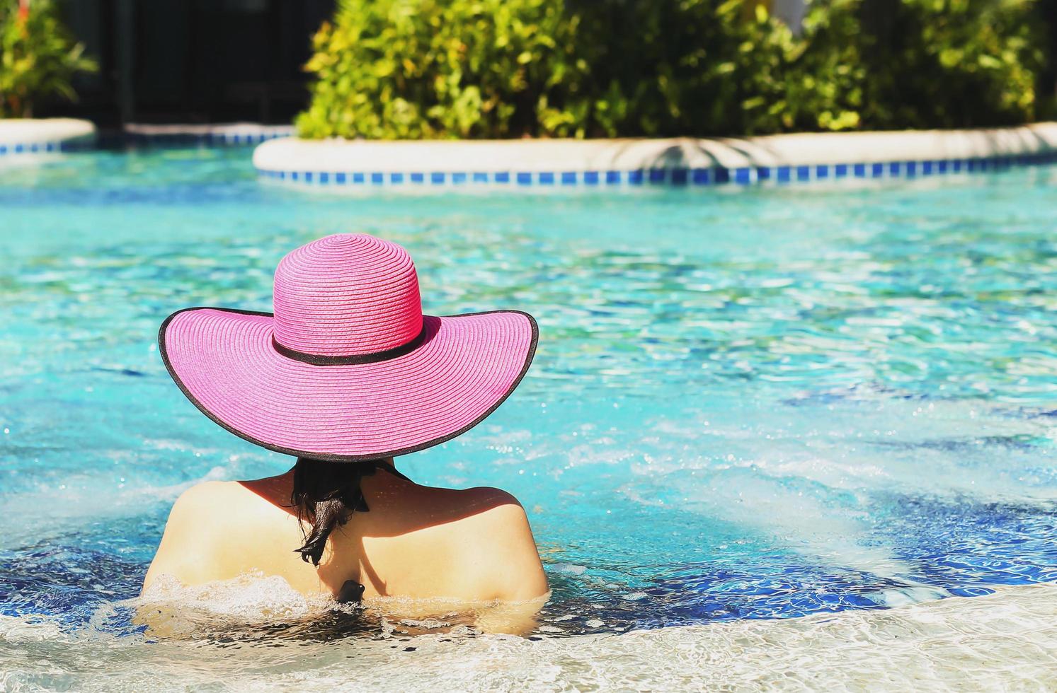 Frau im rosa Hut, der im Schwimmbad entspannt foto