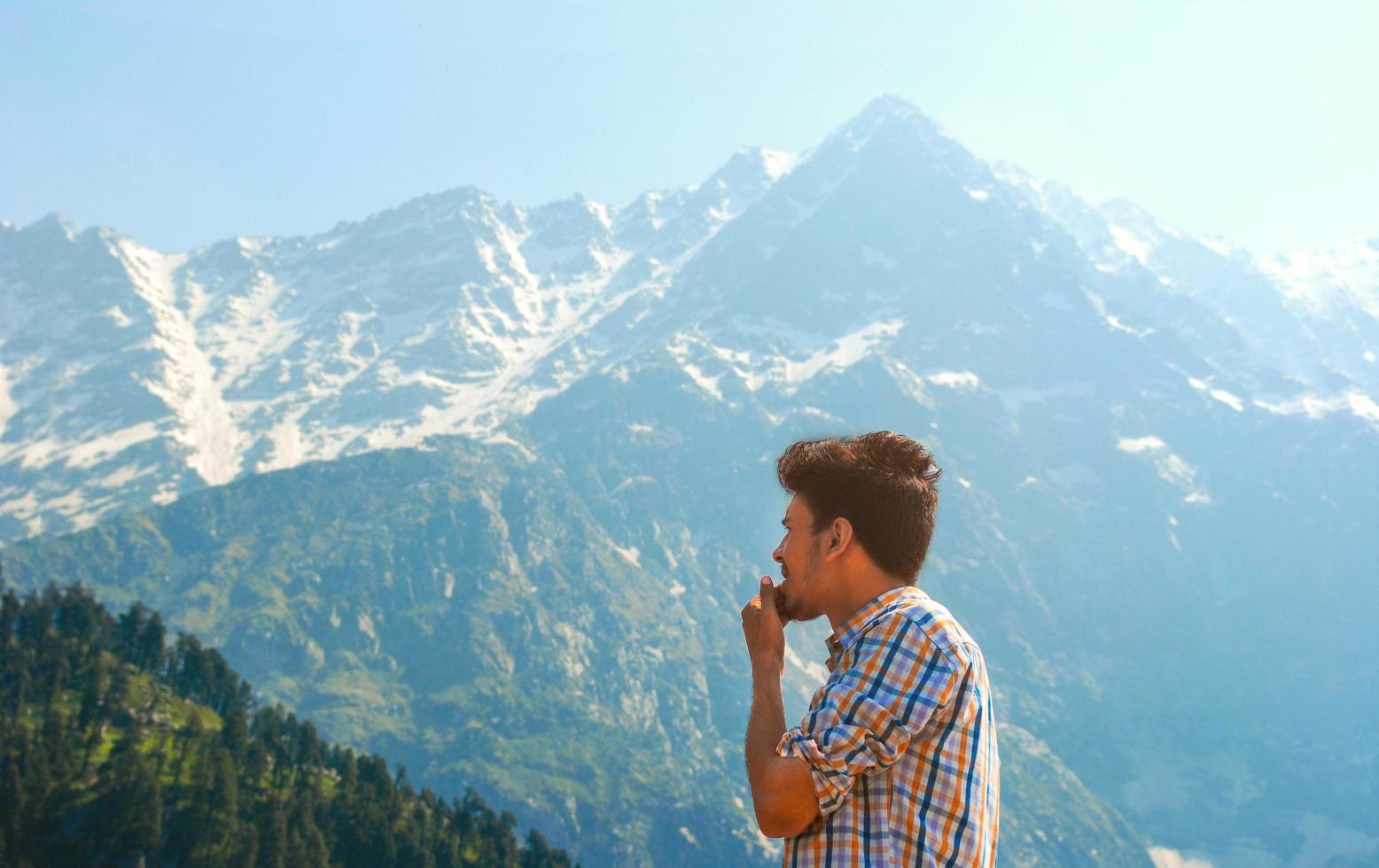 Mann im Plaid, der Berge und Bäume betrachtet foto