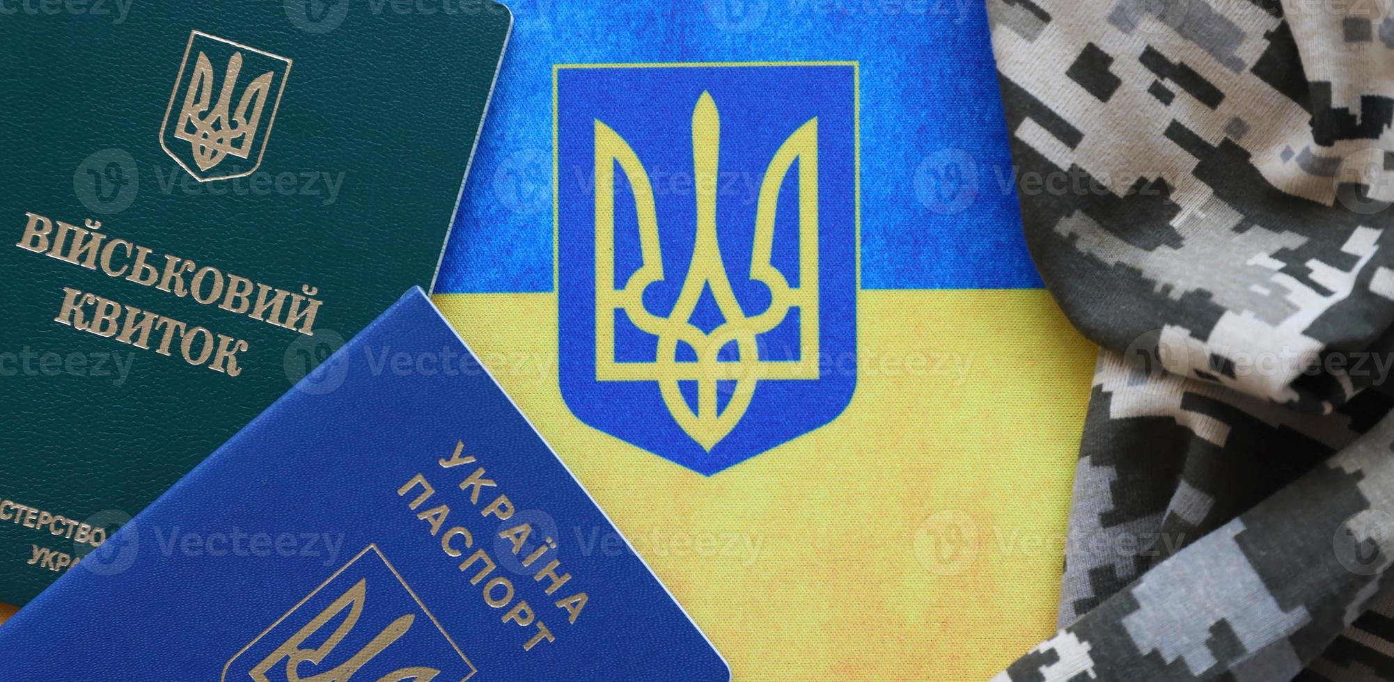 ukrainischer militärausweis und ausländischer pass auf stoff mit textur aus pixeliger tarnung. Stoff mit Tarnmuster in grauen, braunen und grünen Formen mit persönlichem Token und Reisepass der ukrainischen Armee. foto