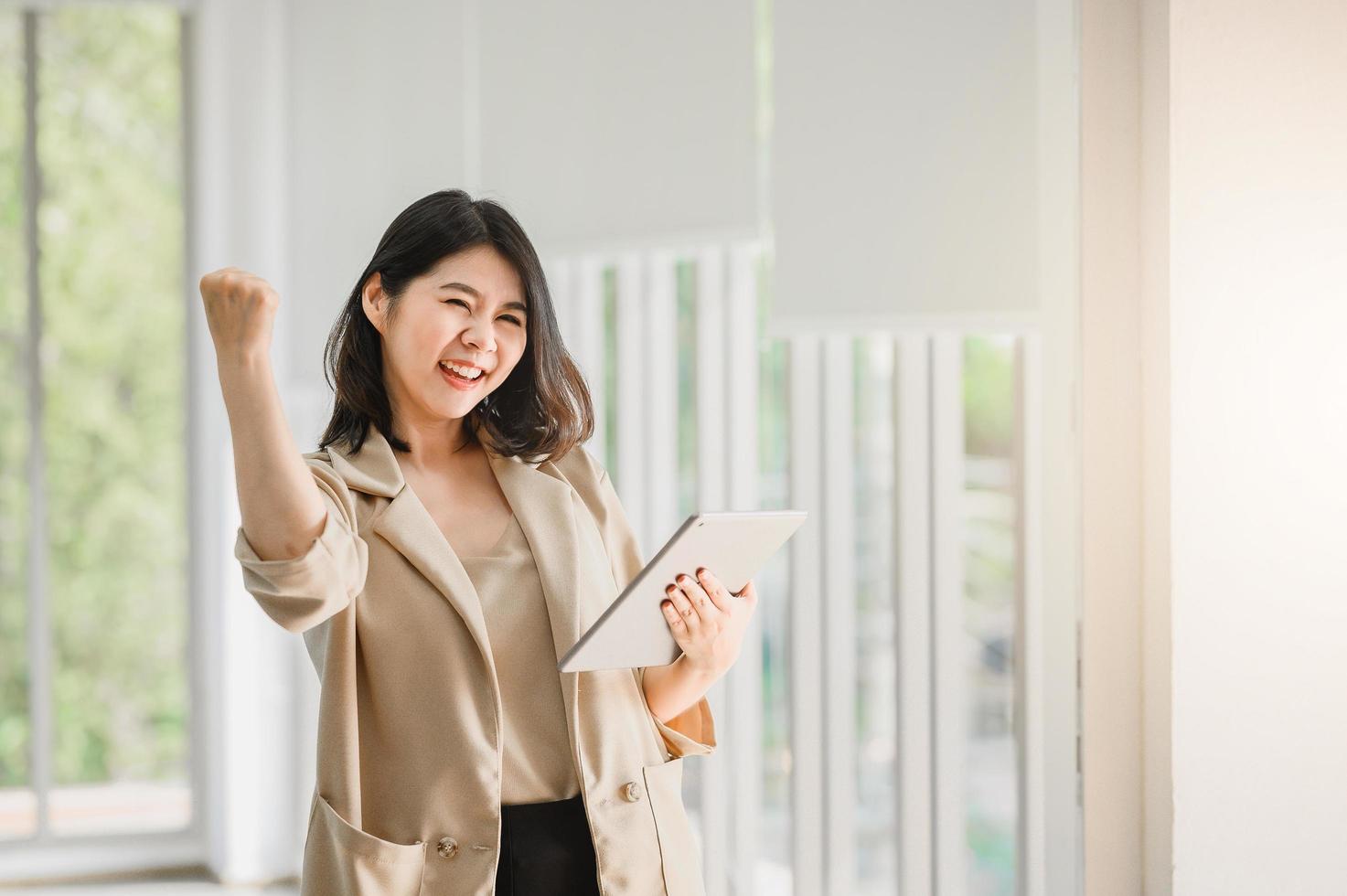 asiatische Frau, die digitales Tablett hält und ihren Arm anhebt foto