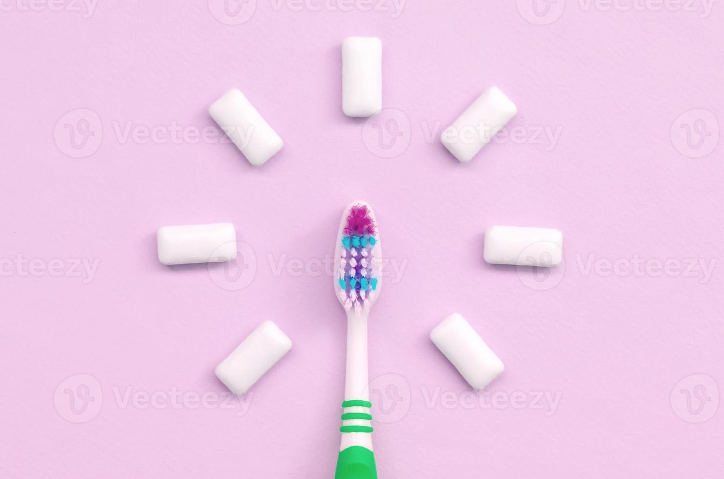 Zahnbürste und Kaugummis liegen auf einem pastellrosa Hintergrund foto