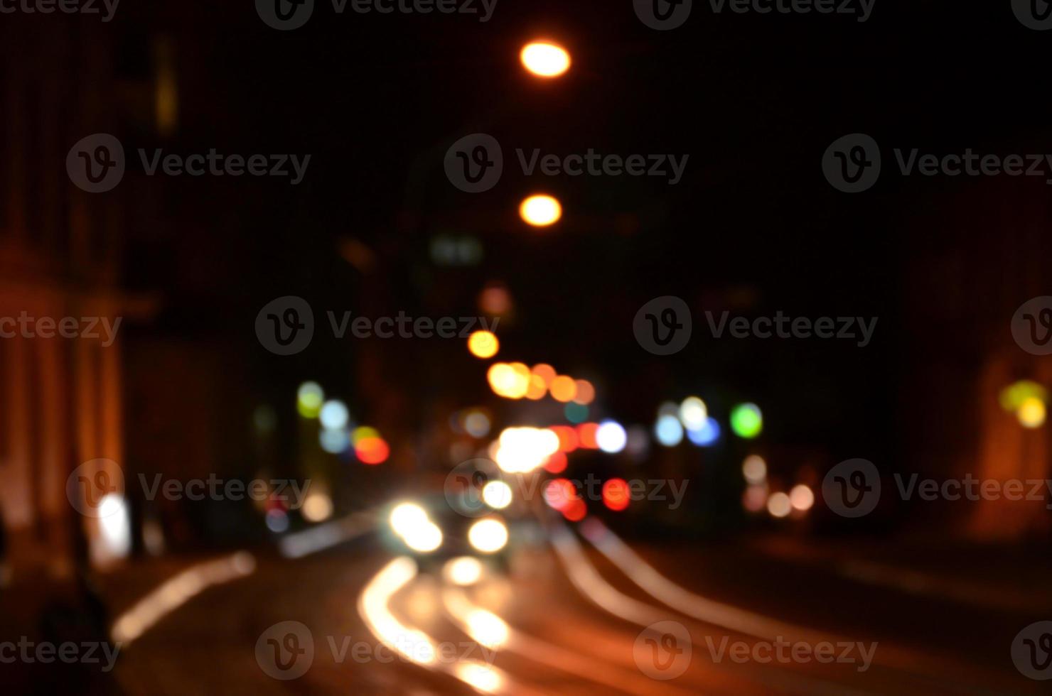 verschwommene Nachtszene des Verkehrs auf der Fahrbahn. defokussiertes Bild von Autos, die mit leuchtenden Scheinwerfern fahren. Bokeh-Kunst foto