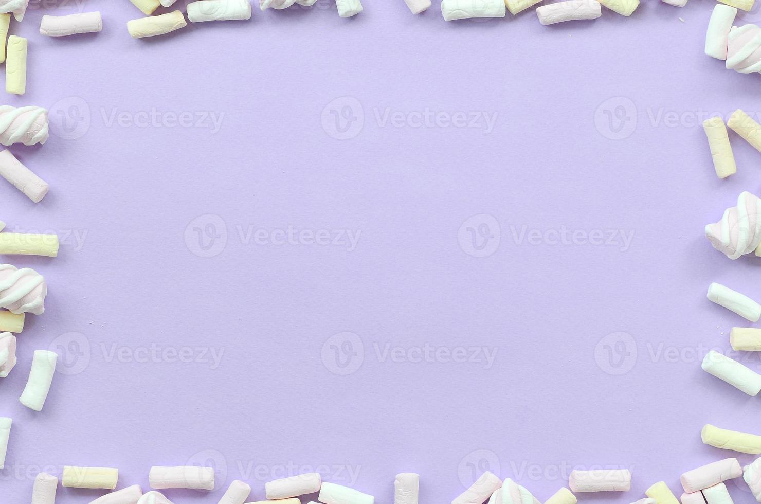 bunter Marshmallow auf violettem Papierhintergrund. pastellkreativer strukturierter rahmen. minimal foto