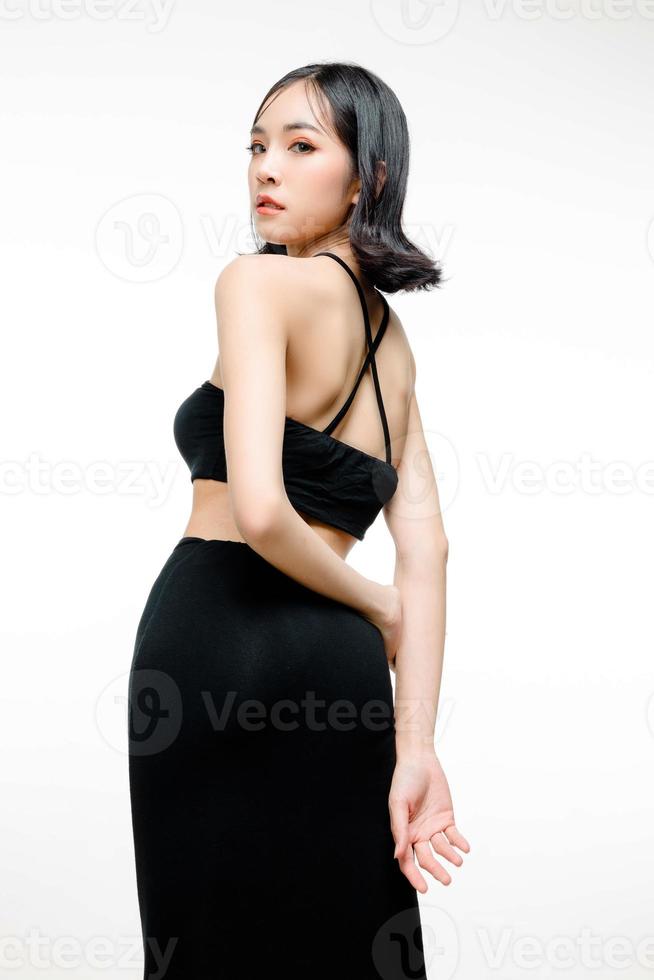 Modische asiatische Frau mit kurzen Haaren und perfektem Körper. süßes weibliches Modell mit natürlichem Make-up und funkelnden Augen auf weißem, isoliertem Hintergrund. gesichtsbehandlung, kosmetik, schönheitskonzept. foto