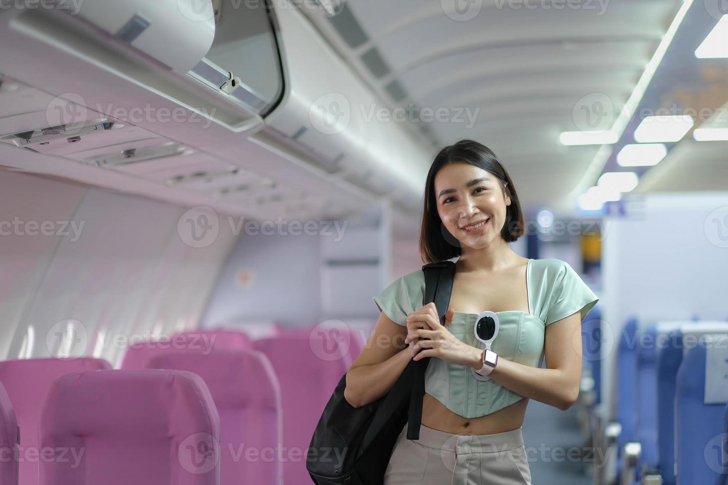 Porträt einer Frau, die einen Koffer über der Schulter trägt, während sie in einem Passagier eines Flugzeugs steht. foto