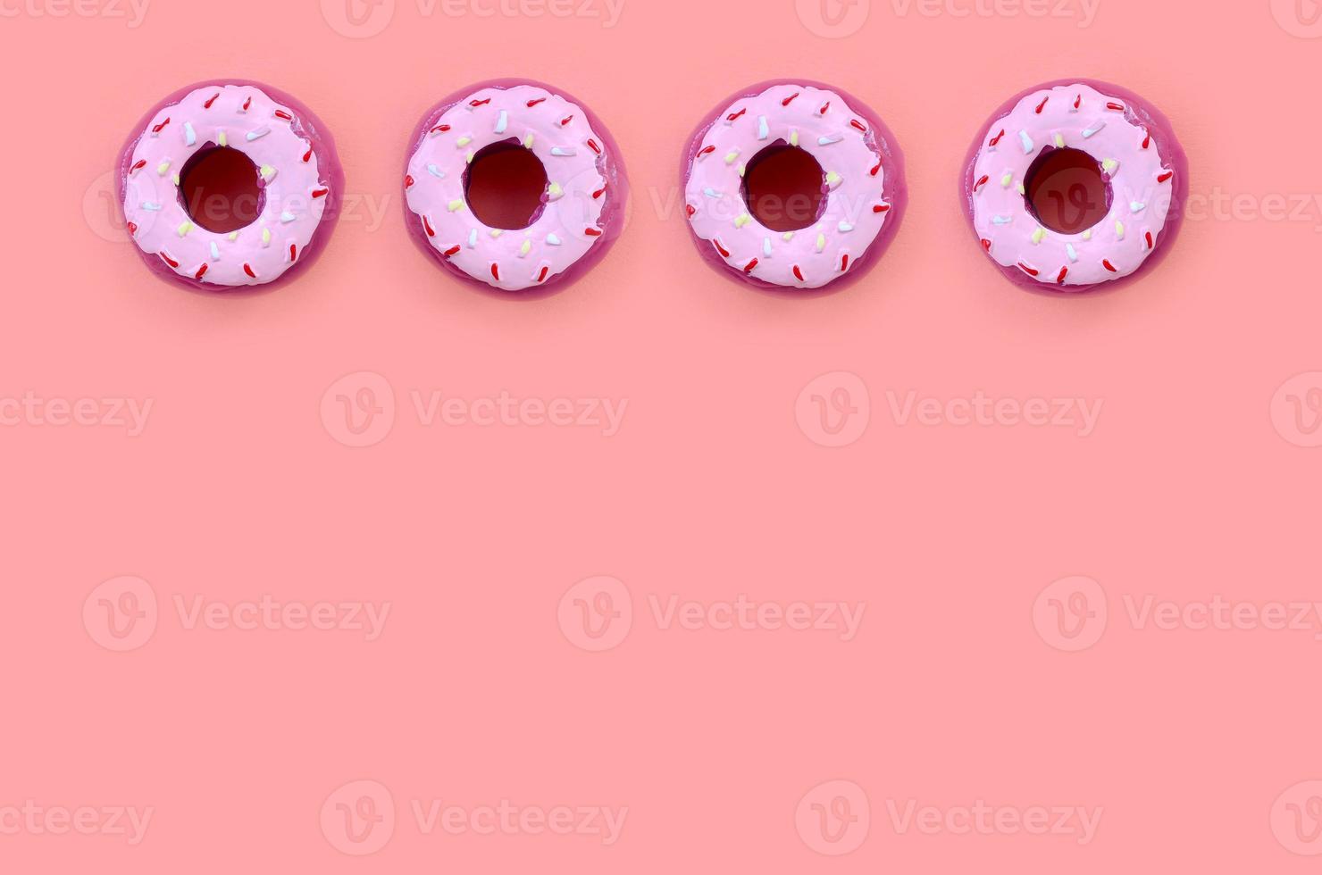 Viele kleine Plastikdonuts liegen auf einem pastellfarbenen Hintergrund. flaches minimales muster. Ansicht von oben foto