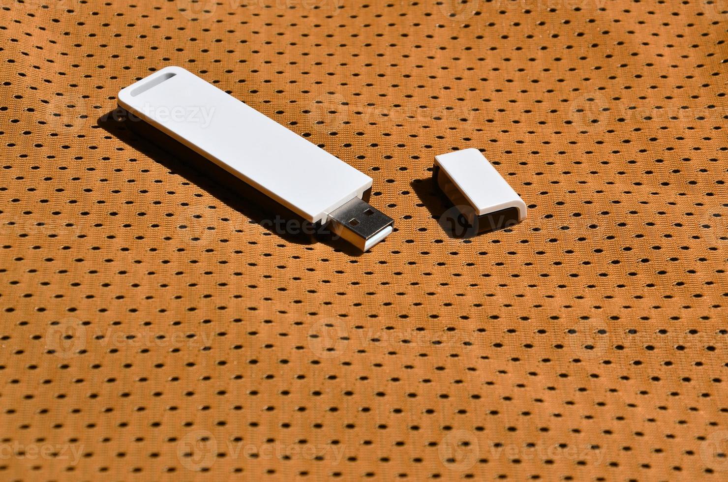 Auf der orangefarbenen Sportbekleidung aus Polyester-Nylonfaser wird ein moderner tragbarer USB-WLAN-Adapter platziert foto
