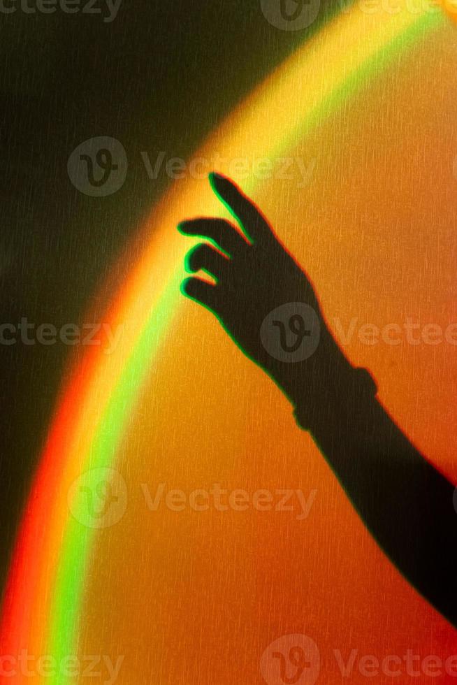 Schatten der Hand der Frau. Regenbogenreflexion des Sonnenstrahls an der Wand. Hand berührt Regenbogen. foto