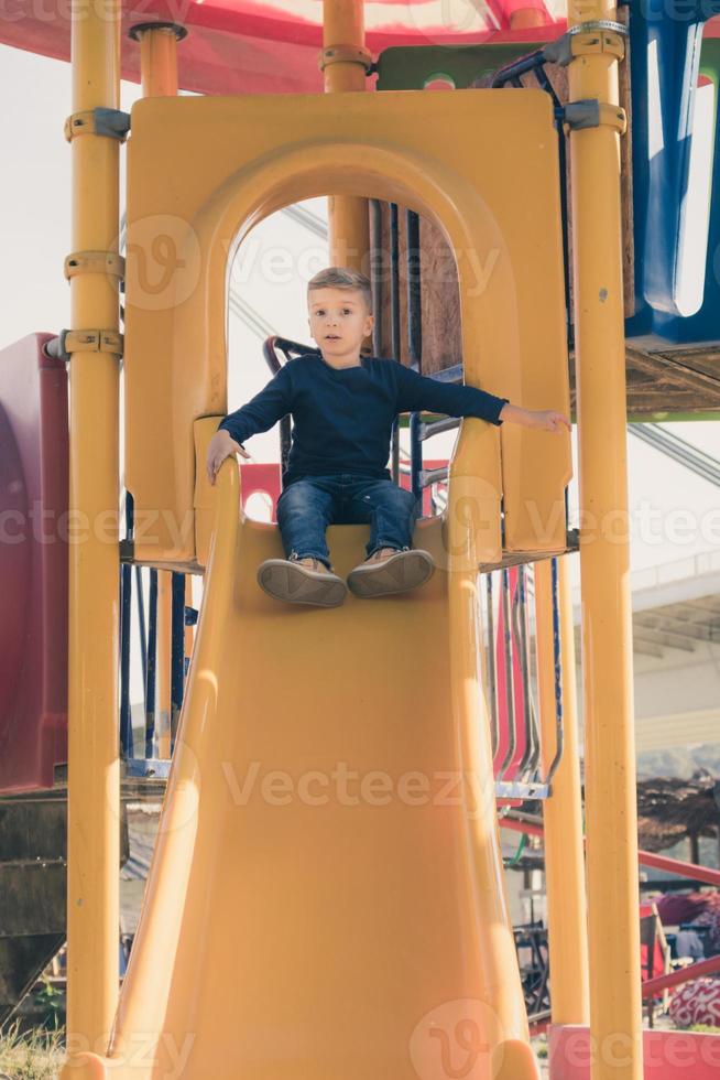 kleiner Junge, der auf dem Spielplatz rutscht. foto