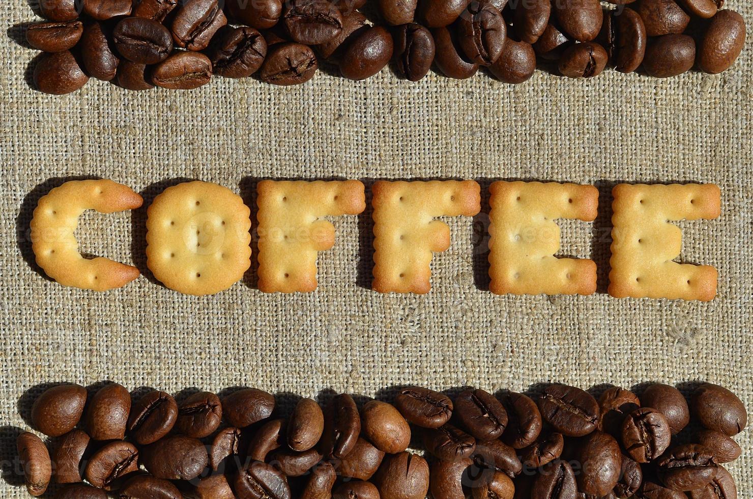 Kaffee. das wort aus den essbaren buchstaben liegt auf der grauen leinwand mit kaffeebohnen foto