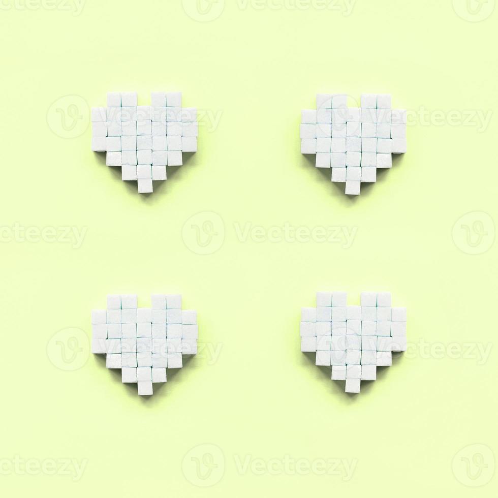 Ein paar Herzen aus Zuckerwürfeln liegen auf einem trendigen Pastell-Limone foto
