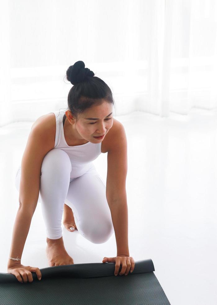 Frau rollt Yogamatte auf foto