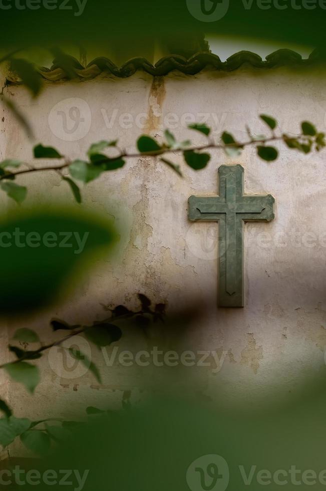 Religion kreuzen. Symbol. Verehrung. Kreuz auf abgenutzter Wand zwischen Vegetation, Pflanze unscharf und Fliesen auf der Oberseite, Mexiko foto