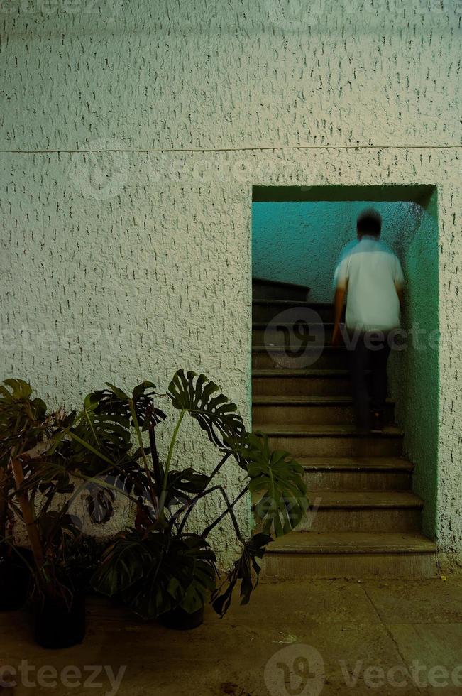 Person beim Treppensteigen in einem Raum regionalistischer Architektur mit grünen Farben und Licht foto