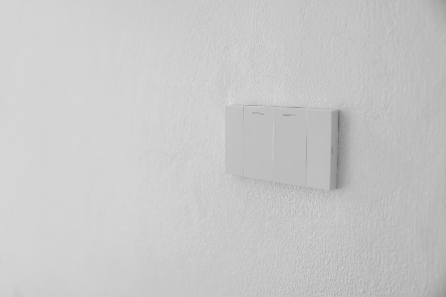 Lichtschalter, mechanischer Schalter aus weißem Kunststoff aus nächster Nähe, der an einer weißen Wand montiert ist foto